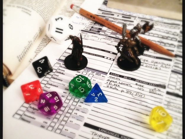 A typical character sheet, your minature or hero and the many dice needed to play.